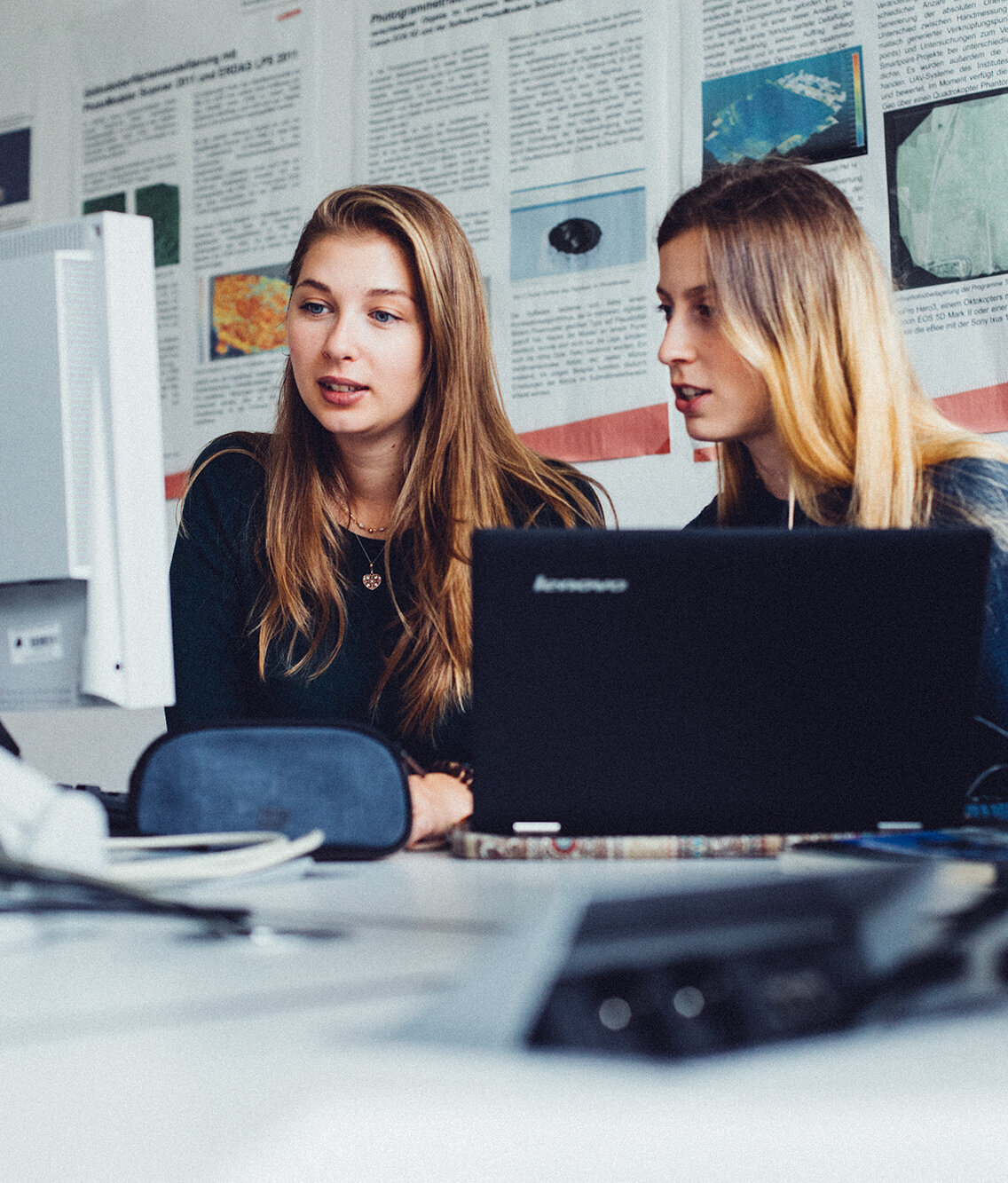 two young women sitting in front of laptops
