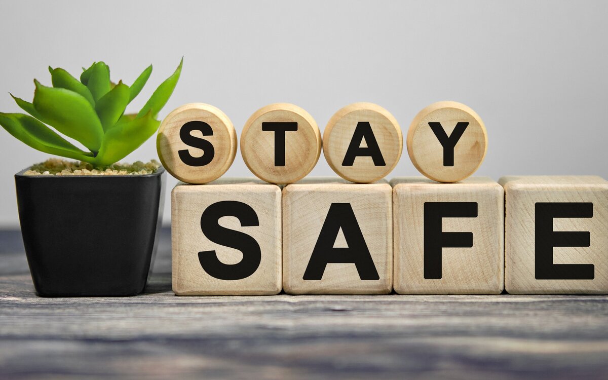 STAY SAFE - text on wooden cubes, green plant in black pot on a wooden background