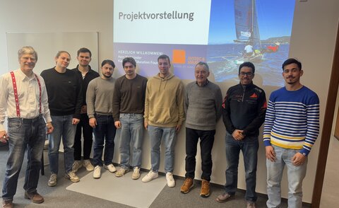 ecosail team standing in front of projection of a boat