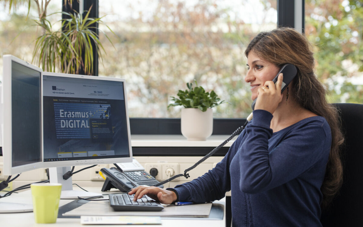 administrative person sitting in front of a computer monitor and talking on the phone