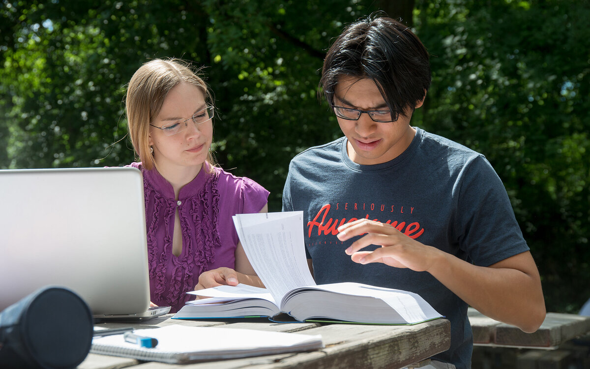 two students working together at a table on the campus