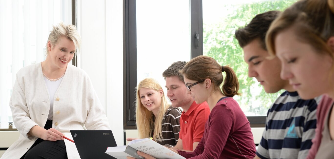 Professorin am Tisch mit einer Gruppe Studierenden