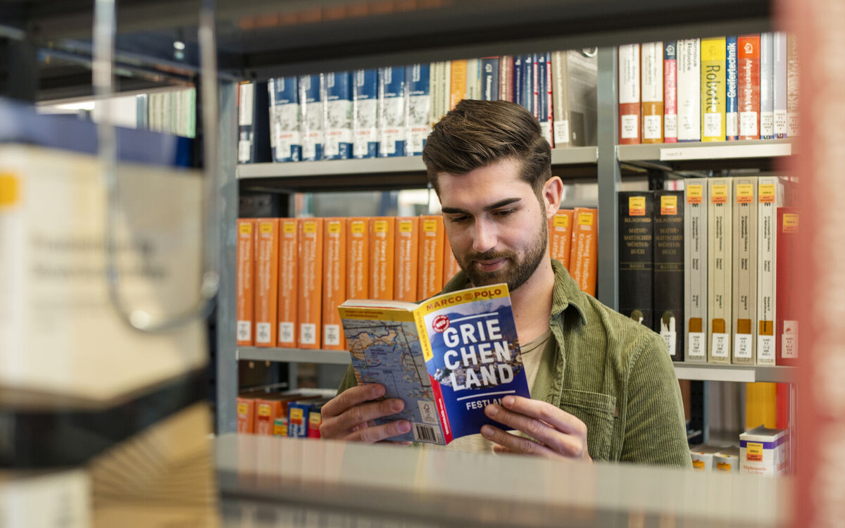 student sitting in the library and reading a book