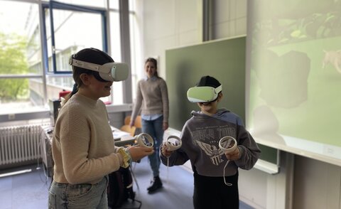 Zwei Teilnehmerinnen des Girls' Day probieren ihre Lernwelten in VR aus, nachdem sie von IIIX Mitarbeiterin Darja Stepanova (hinten) eine Einführung erhielten.