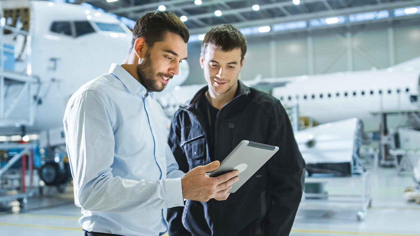 two engineers looking at tablet in aircraft hangar