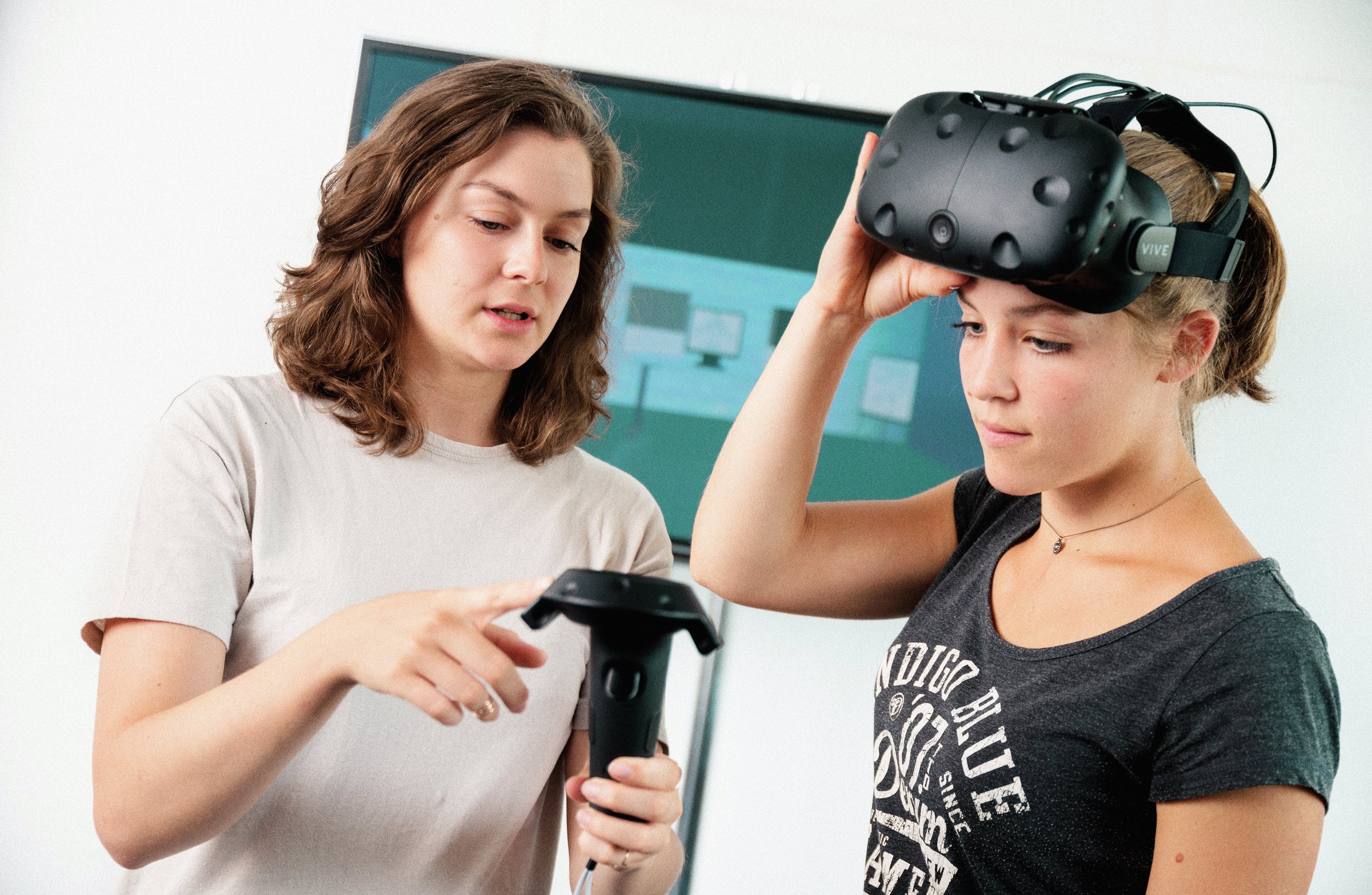 a female student explaining equipment to a fellow student wearning VR goggles