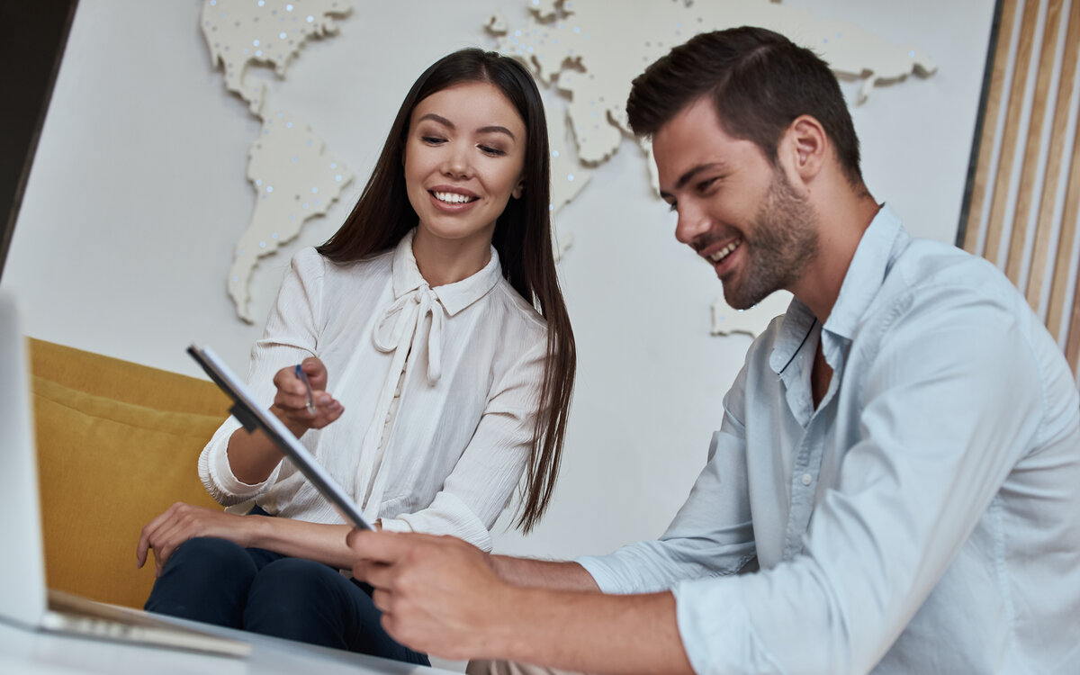 Mann und Frau besprechen Dokumente vor Weltkarte