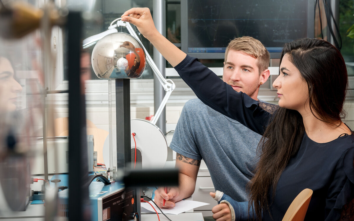 student at the lab, holding up a silver hemisphere