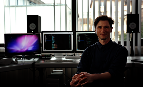 Prof. Moritz Schell vor Bildschirmen mit Code