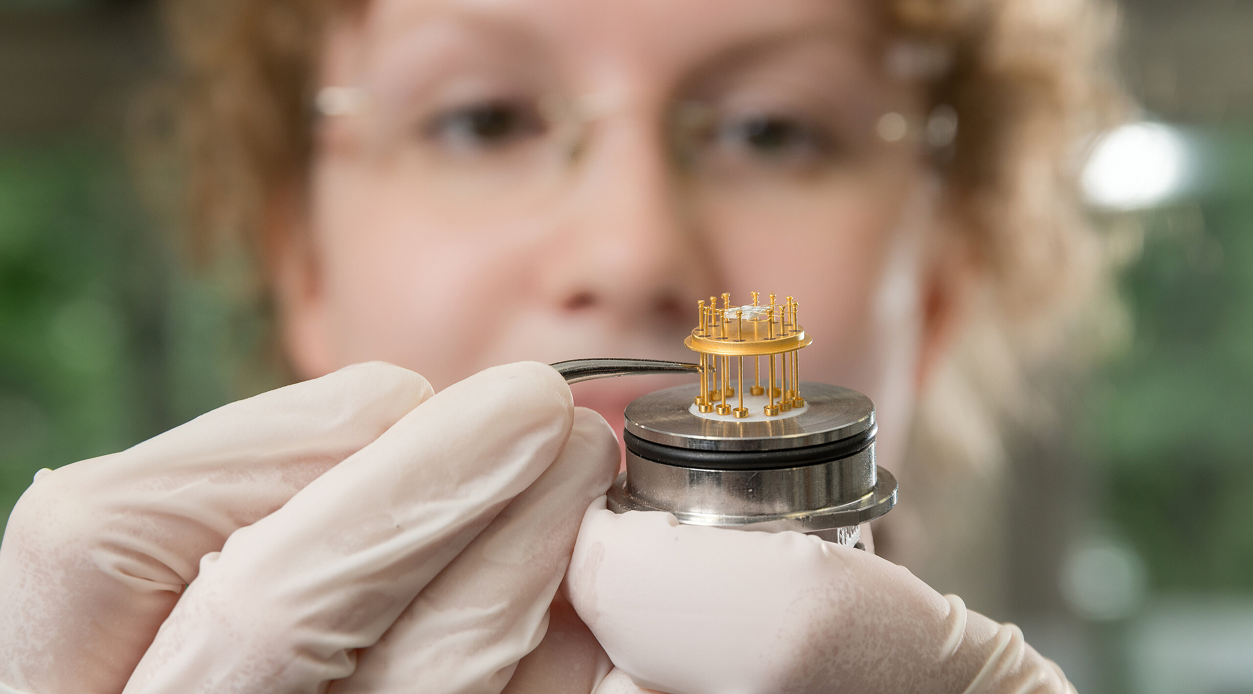 close-up of a small sensor being shown by a woman wearing medical gloves