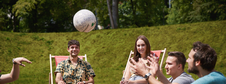 Das Bild zeigt Studierende beim Ballspiel auf dem Campus