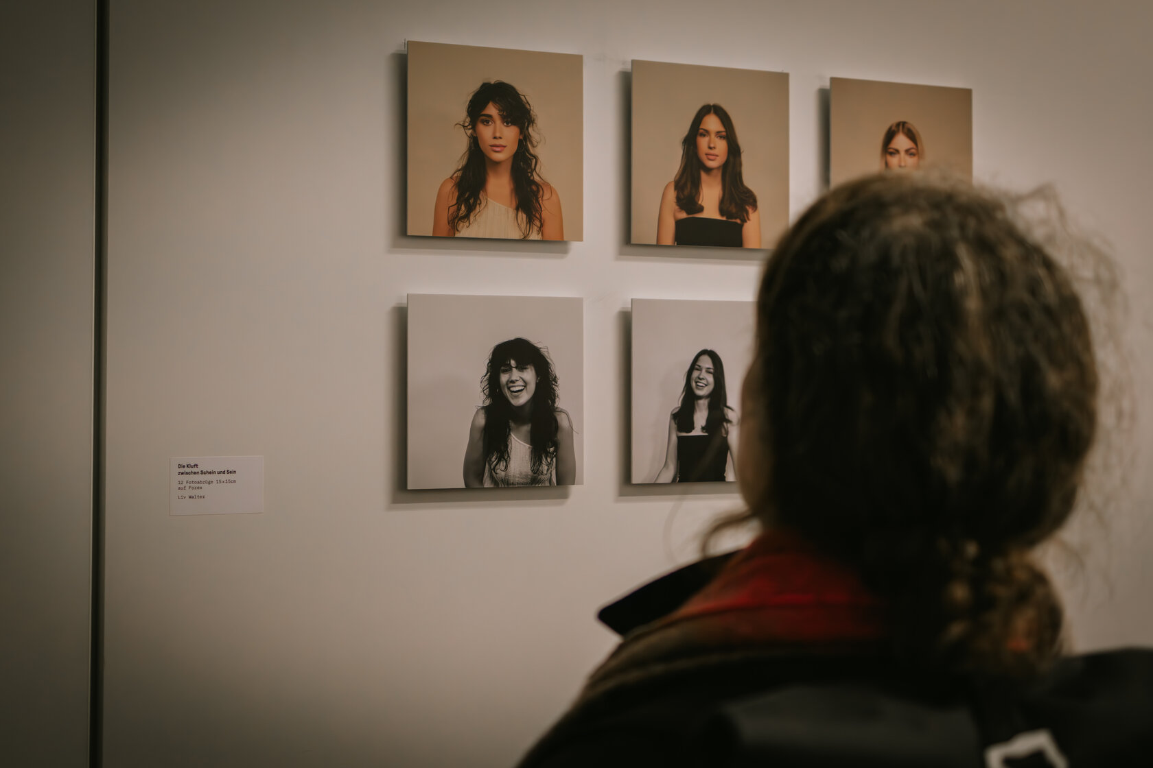 Frau schaut sich ausgestellte Fotos an: „Die Kluft zwischen Schein und Sein“ von Liv Walter
