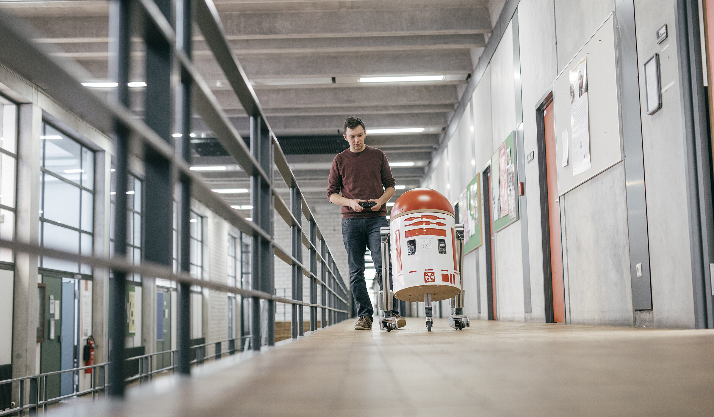 student walking a robot along the hallway of the HKA lab wing