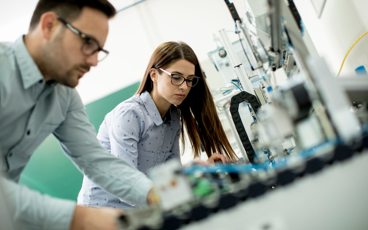 two students working at a machine in the lab