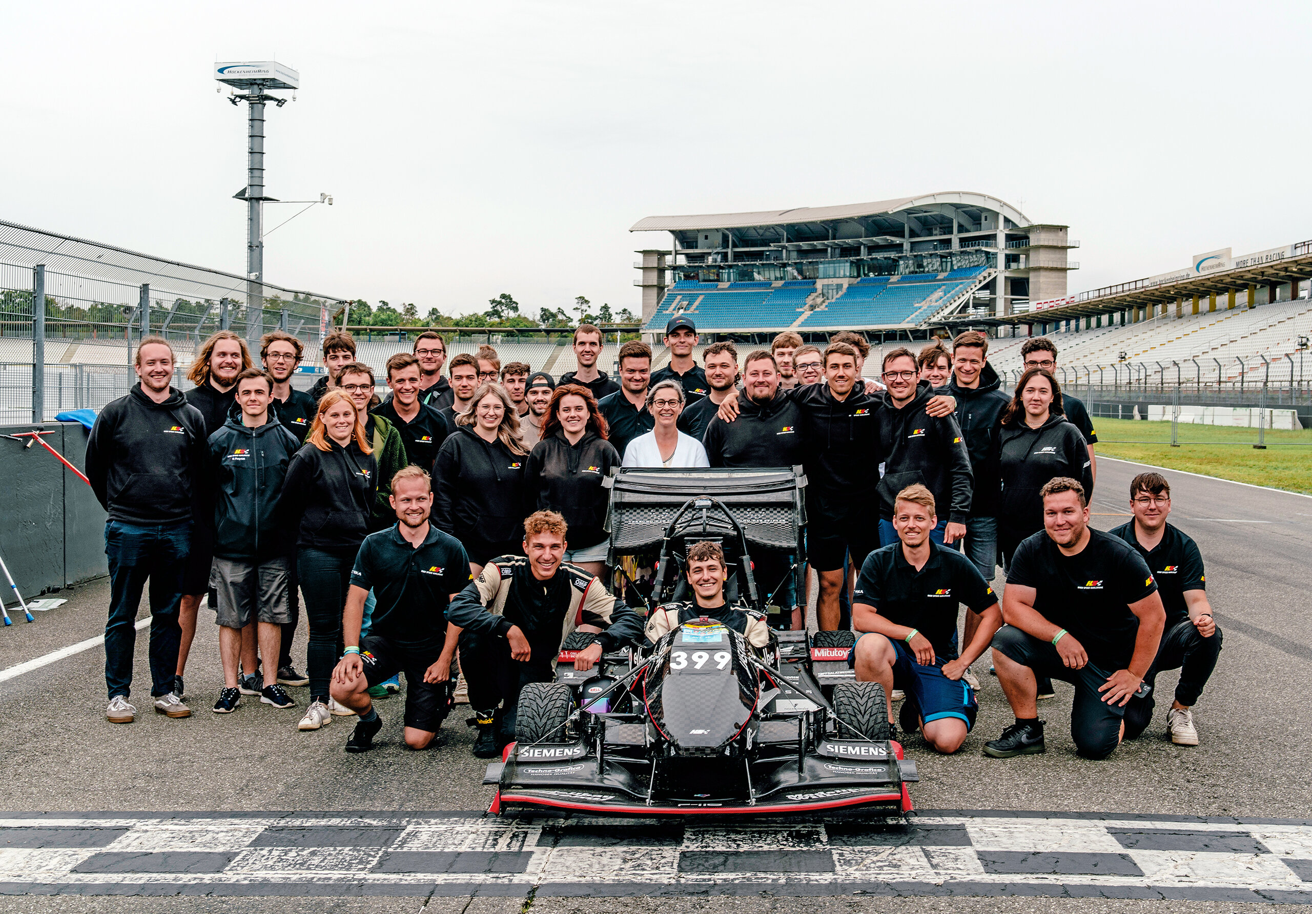 HKA High Speed team and their racing car posing on the track