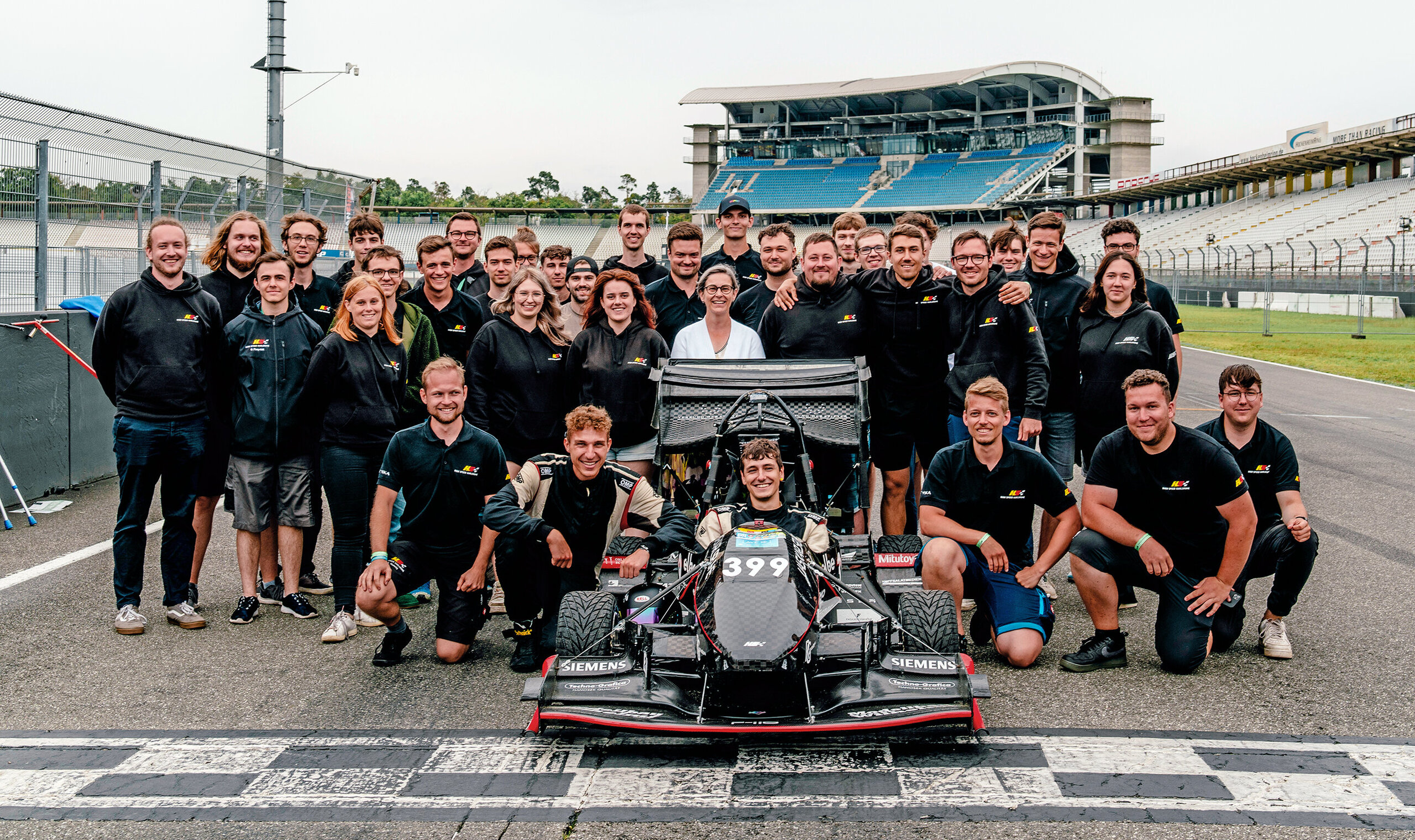 HKA High Speed team and their racing car posing on the track