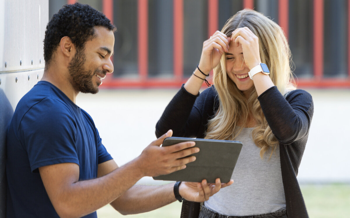 student using a tablet to show a fellow student some information