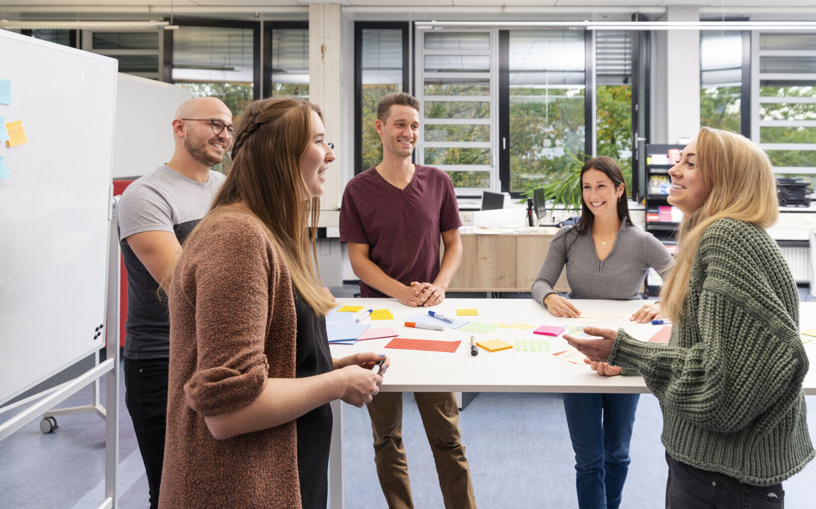 F&uuml;nf Menschen unterhalten sich an einem Stehtisch. 
