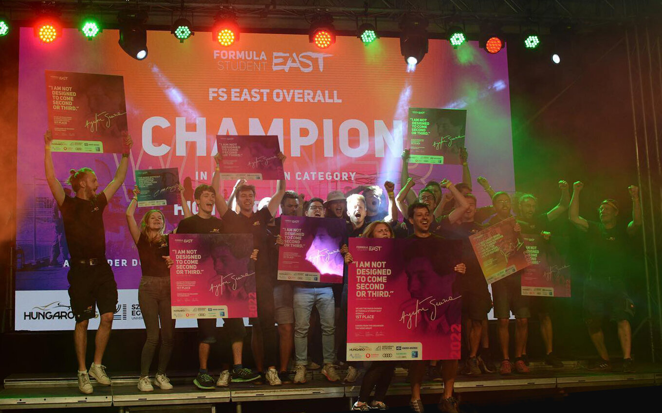 group of students on a stage, holding placards and cheering