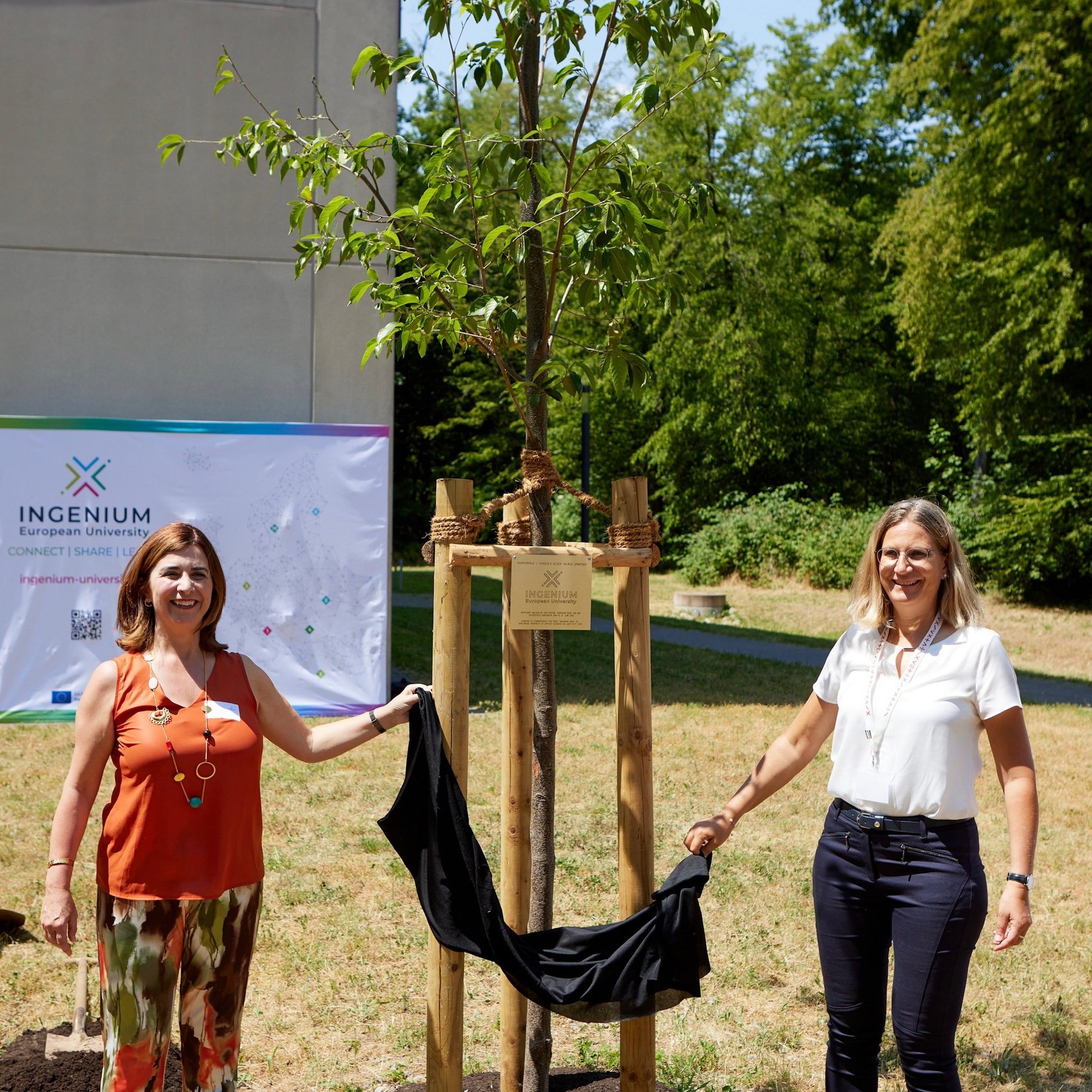 two professors unveiling the plaque on the comemorative tree