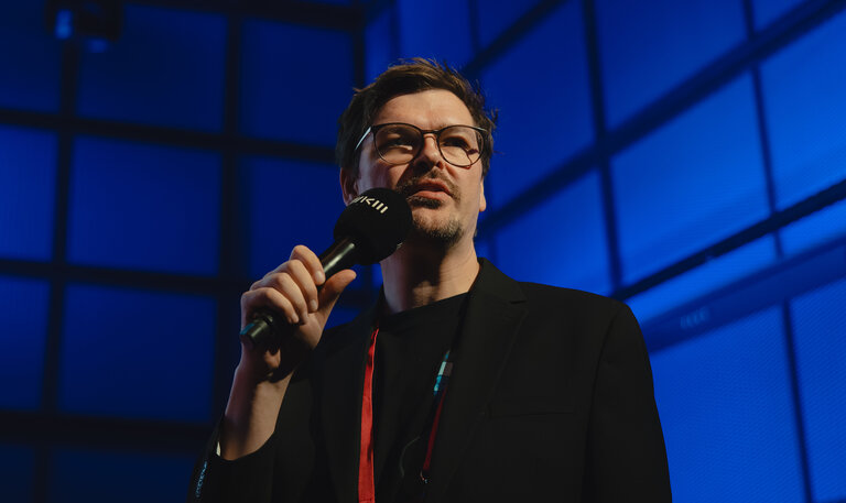 Daniel Hepperle steht mit einem Mikrofon auf einer B&uuml;hne.