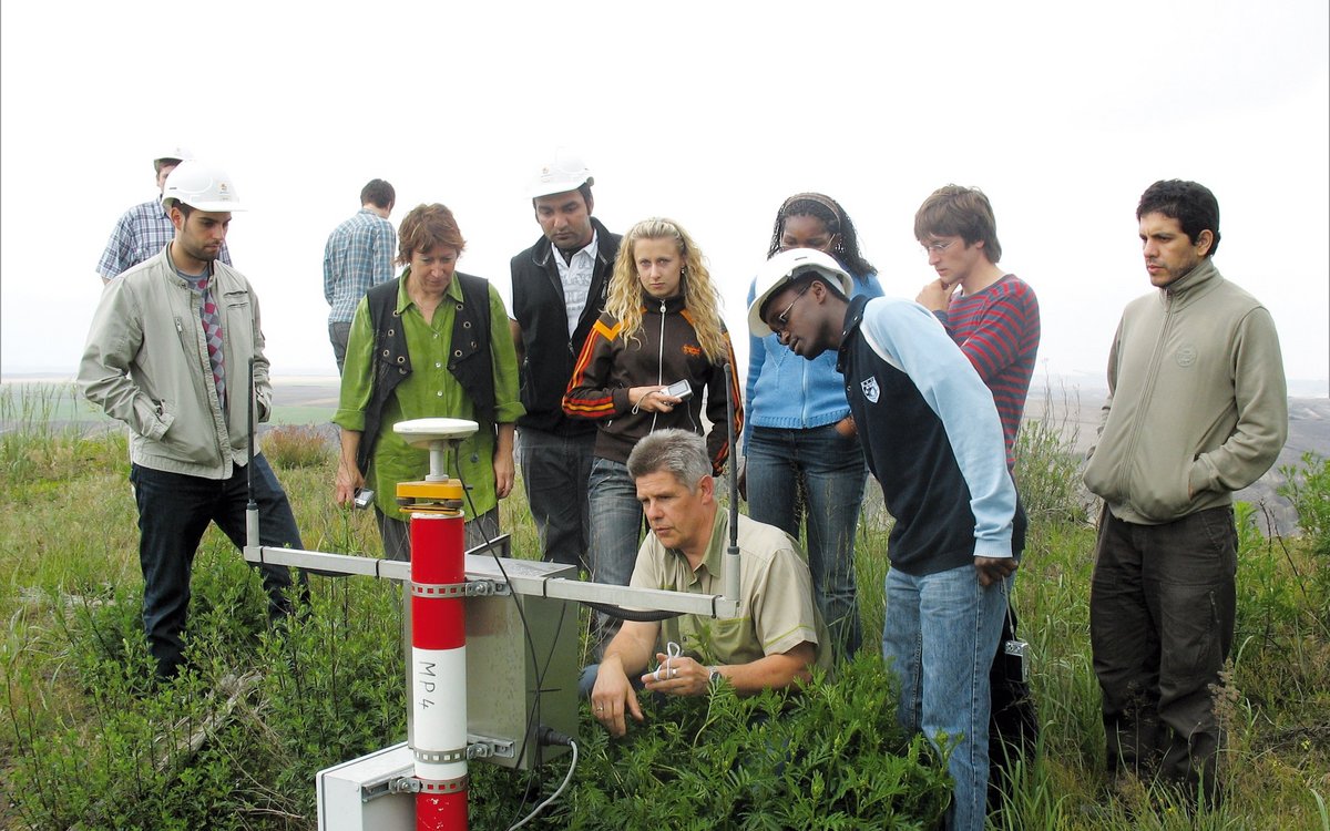 group of students on field work, gathered around the lecturer and a tool