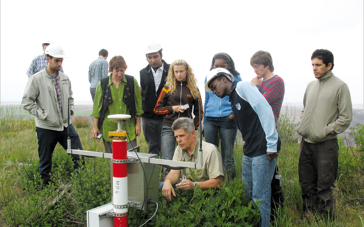 group of students on field work, gathered around the lecturer and a tool